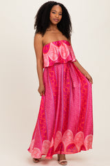 woman wearing a pink strapless maxi dress with a ruffled top and a patterned skirt