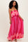 woman wearing a pink strapless maxi dress with a ruffled top and a patterned skirt