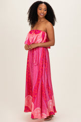 woman wearing a pink strapless maxi dress with a layered ruffle top and bold print patterns