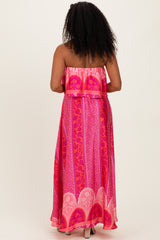 woman wearing a strapless pink maxi dress with a vibrant print, showing the back view and flowing fabric