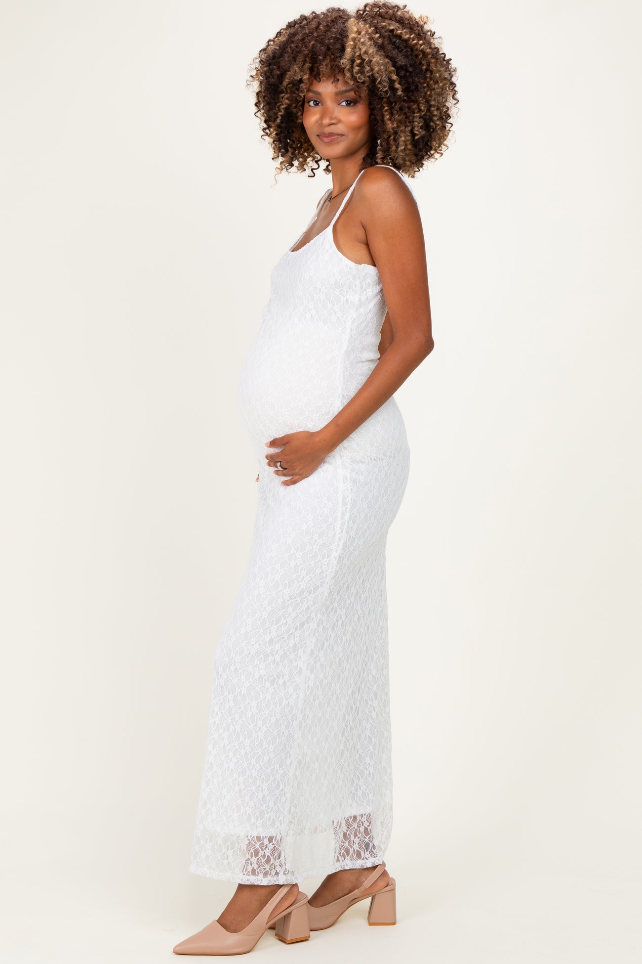 woman wearing a white lace maternity maxi dress and holding her baby bump