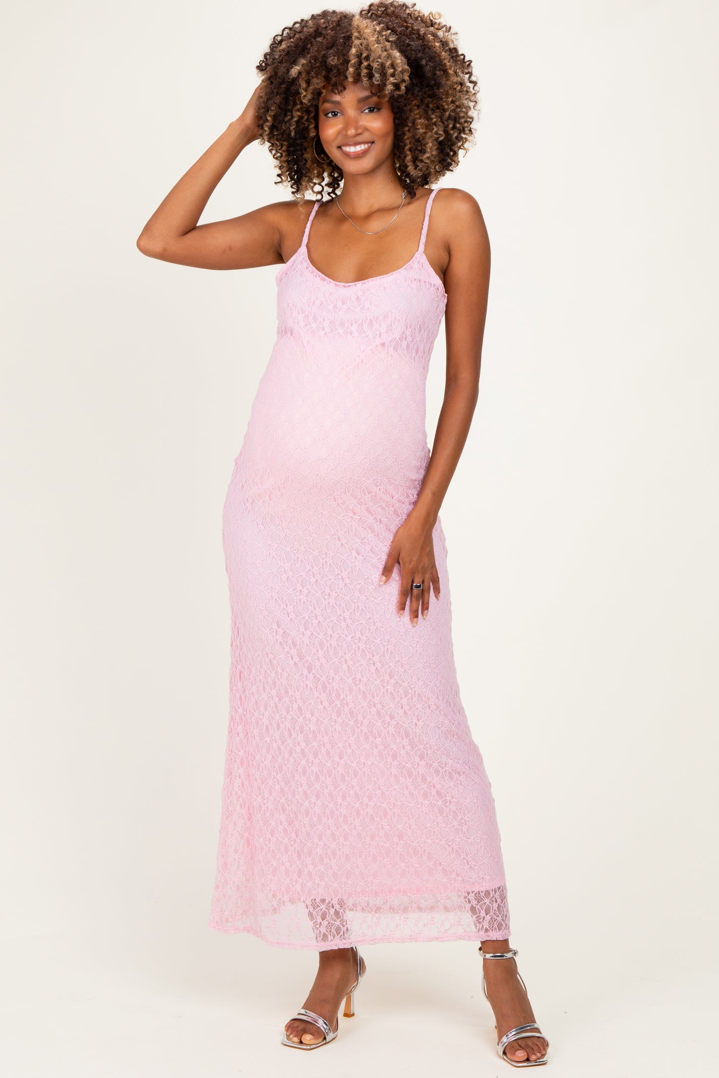 woman wearing a light pink lace maternity dress with spaghetti straps and a visible baby bump