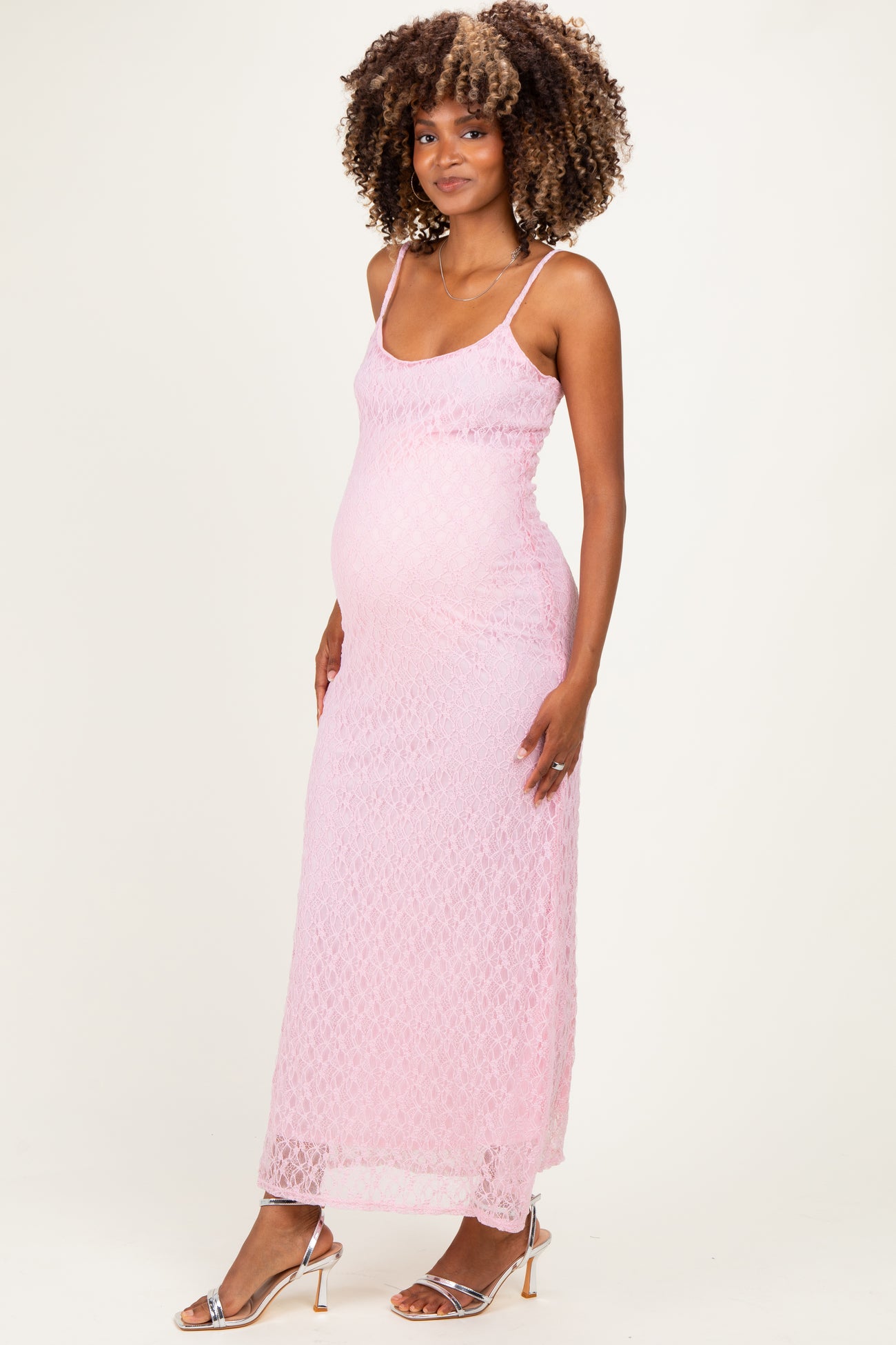 woman wearing a light pink lace maternity dress with spaghetti straps and a visible baby bump
