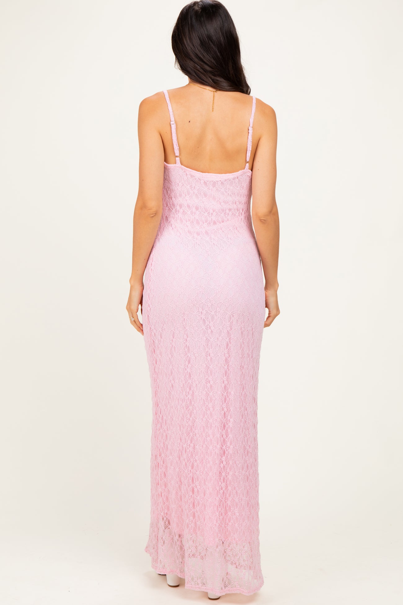 woman wearing a pink lace maxi dress with thin straps, showing the back view