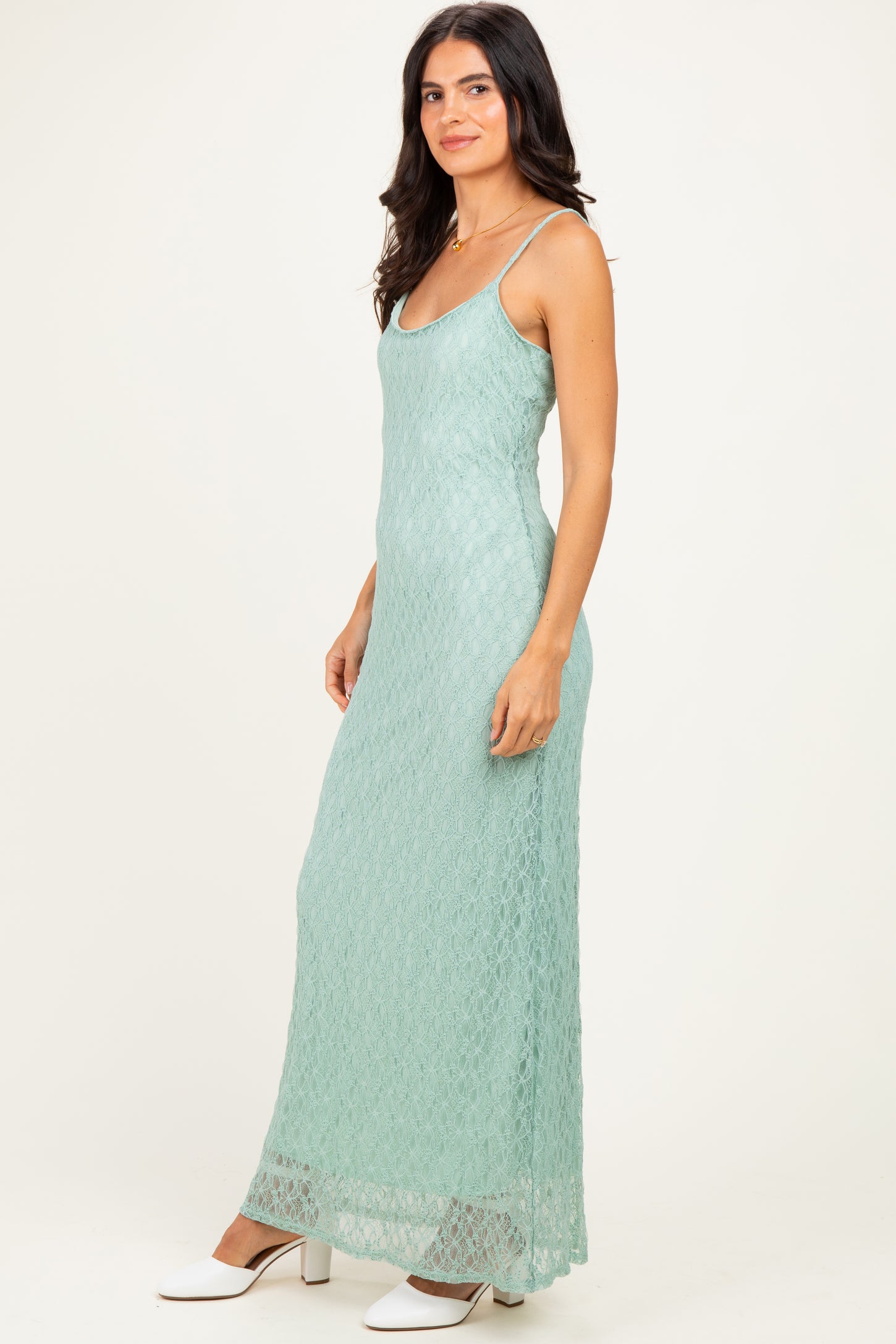woman wearing a light green lace maxi dress with thin straps and a fitted silhouette