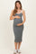 woman wearing a grey maternity midi dress with white straps and holding her baby bump