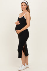 woman wearing a black midi maternity dress with side slits and spaghetti straps, showcasing her baby bump