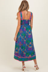 woman wearing a colorful patterned maternity maxi dress with a smocked back and vibrant trim