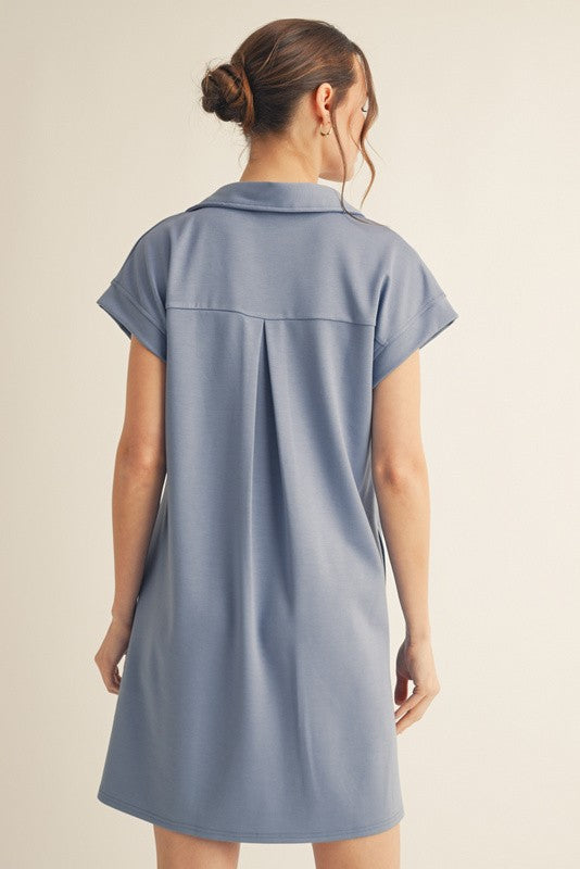 woman wearing a light blue short sleeve polo dress with a back pleat detail