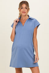 woman wearing a light blue maternity dress with a collar and short sleeves, showing her baby bump