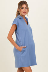 woman wearing a light blue maternity polo dress with short sleeves and pockets, showcasing a baby bump