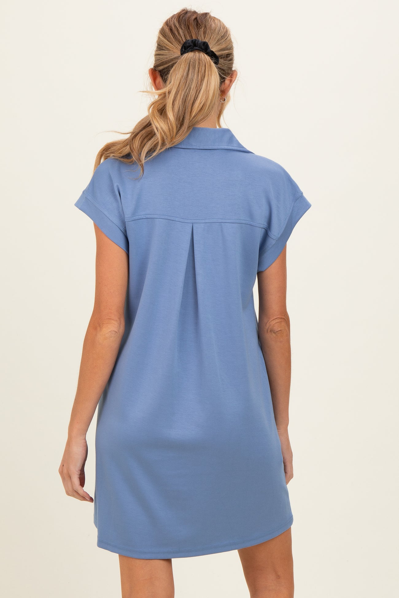 woman wearing a blue maternity dress with a collar and short sleeves, showing a relaxed style from the back