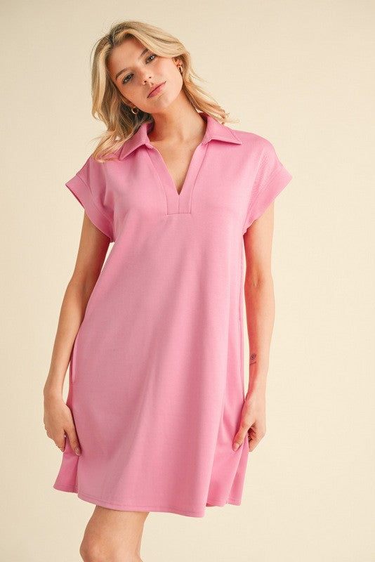 woman wearing a light pink short sleeve polo dress with a v-neck and relaxed fit