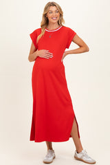 woman wearing a red maternity maxi dress with short sleeves and side slits, holding her baby bump
