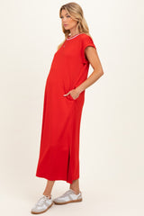 woman wearing a bright red maternity dress with short sleeves, side pockets, and a high slit, showing her baby bump