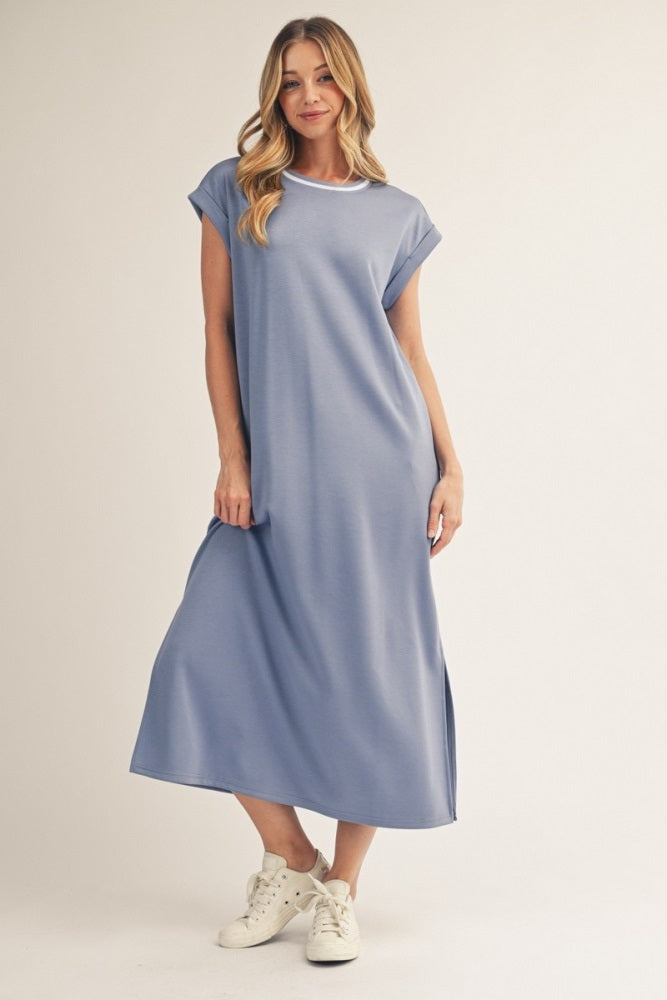 woman wearing a light blue short sleeve maxi dress with side slits and white trim, styled with white sneakers