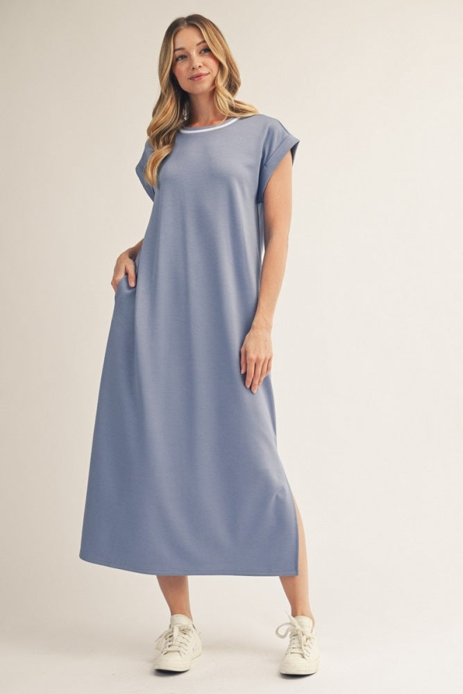 woman wearing a light blue maxi dress with short sleeves and side slits, styled with white sneakers
