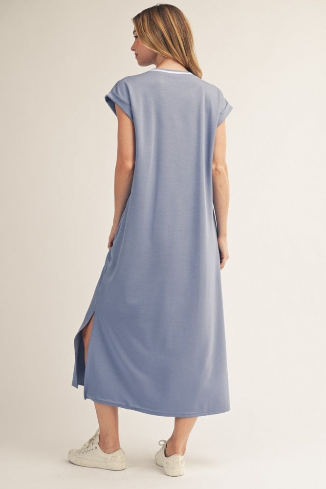 woman wearing a light blue maxi dress with short sleeves and side slits, standing against a neutral background