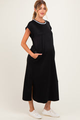 woman wearing a black short sleeve maternity dress with white collar accents and pockets, and a visible baby bump