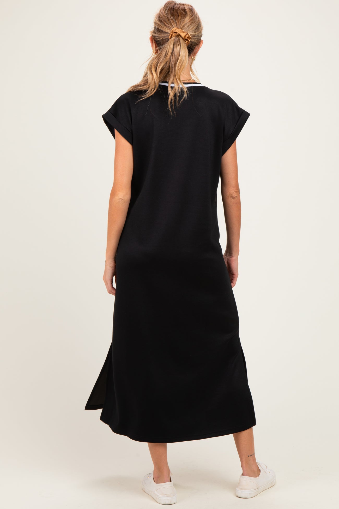 woman wearing a black maternity maxi dress with short sleeves and side slits, showing a relaxed fit