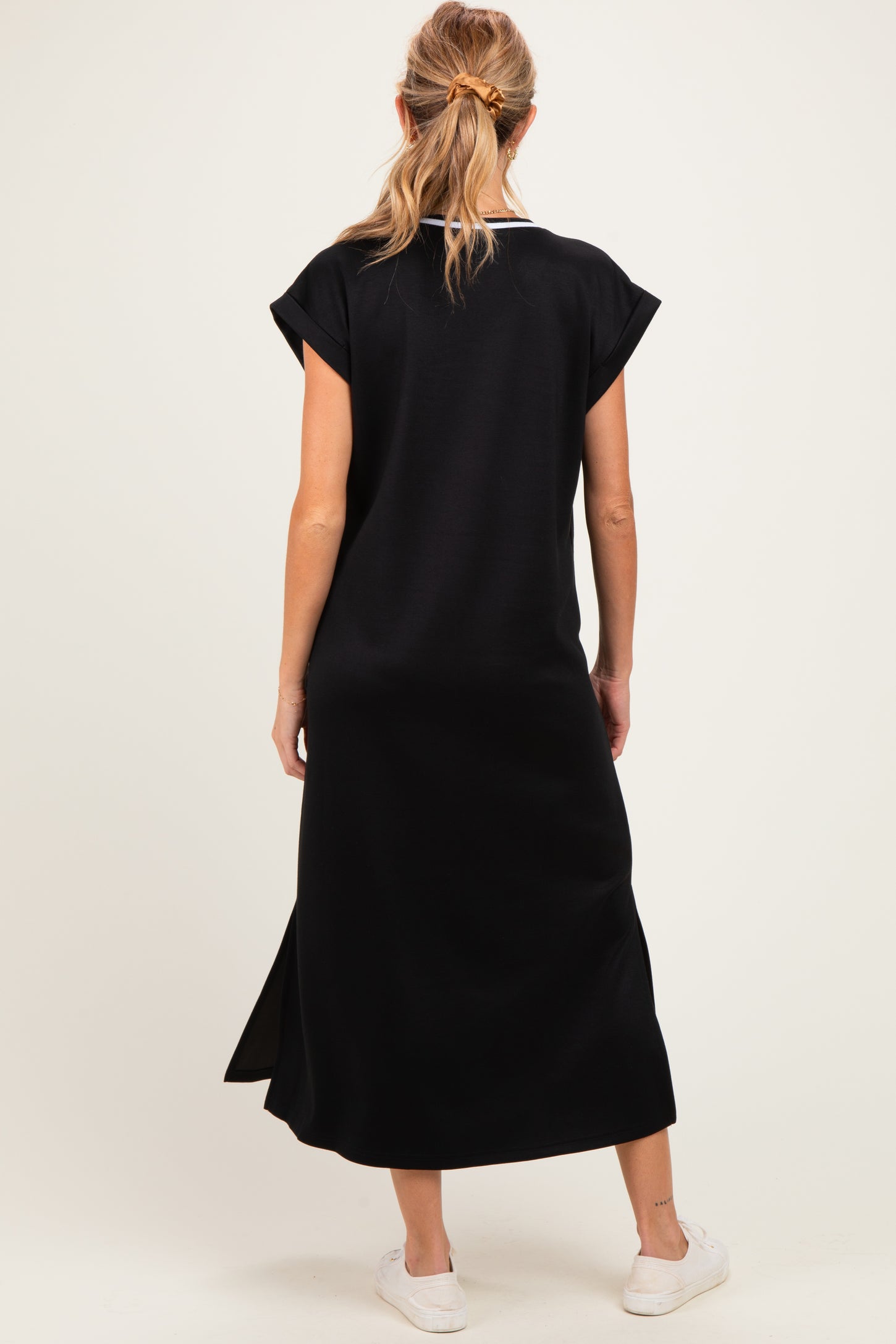 woman wearing a black maternity maxi dress with short sleeves and side slits, showing a relaxed fit