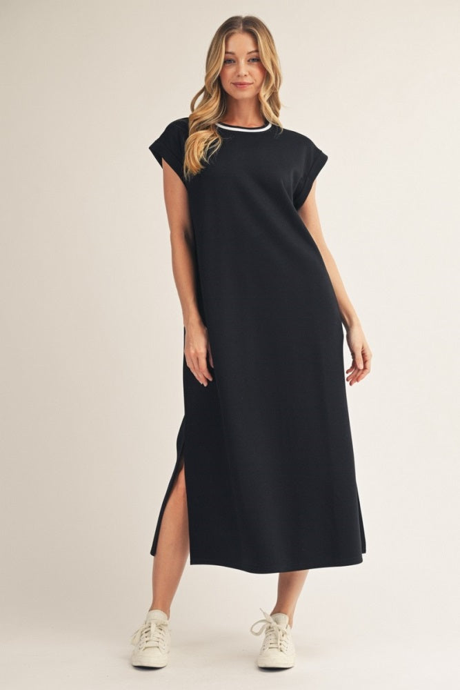 woman wearing a black maxi dress with short sleeves and side slits, paired with white sneakers
