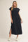 woman wearing a black maxi dress with short sleeves and side slits, paired with white sneakers
