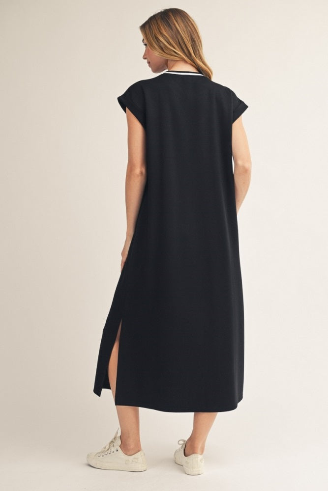 woman wearing a black cap sleeve maxi dress with side slits and white collar, standing against a neutral background