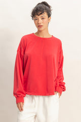 woman wearing a bright red long sleeve oversized sweatshirt with dropped shoulders and a relaxed fit