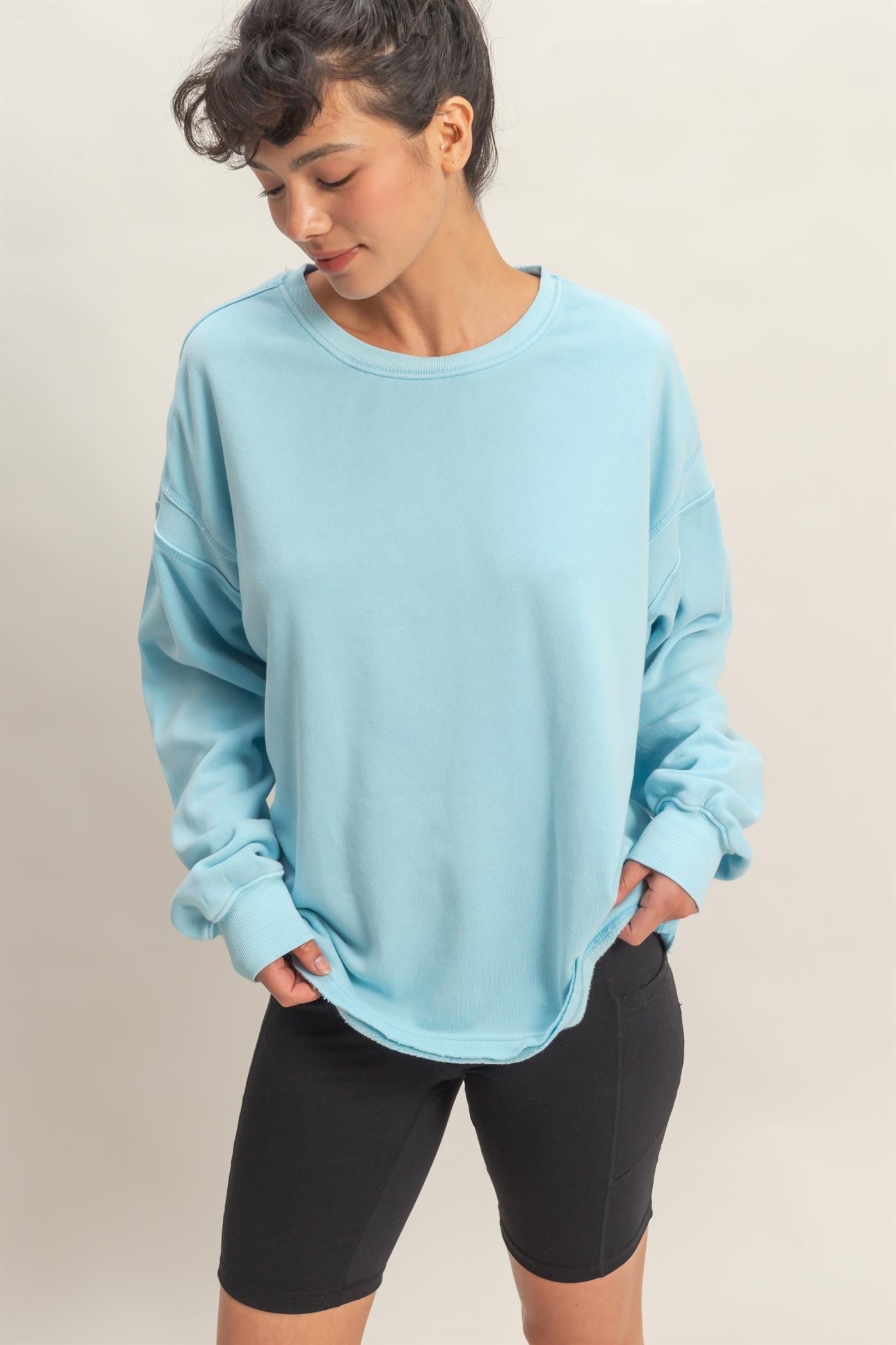 woman wearing a light blue oversized sweatshirt paired with black bike shorts