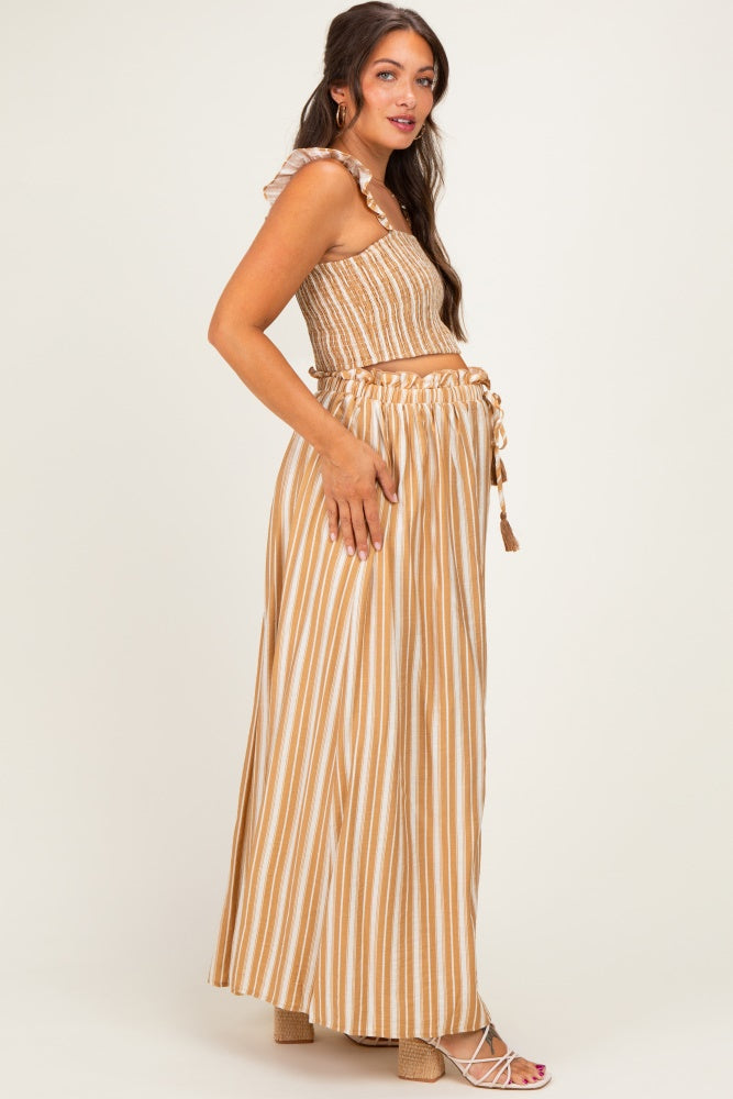 woman wearing a brown and cream striped maternity two-piece set with a ruffled crop top and long skirt, showing her baby bump