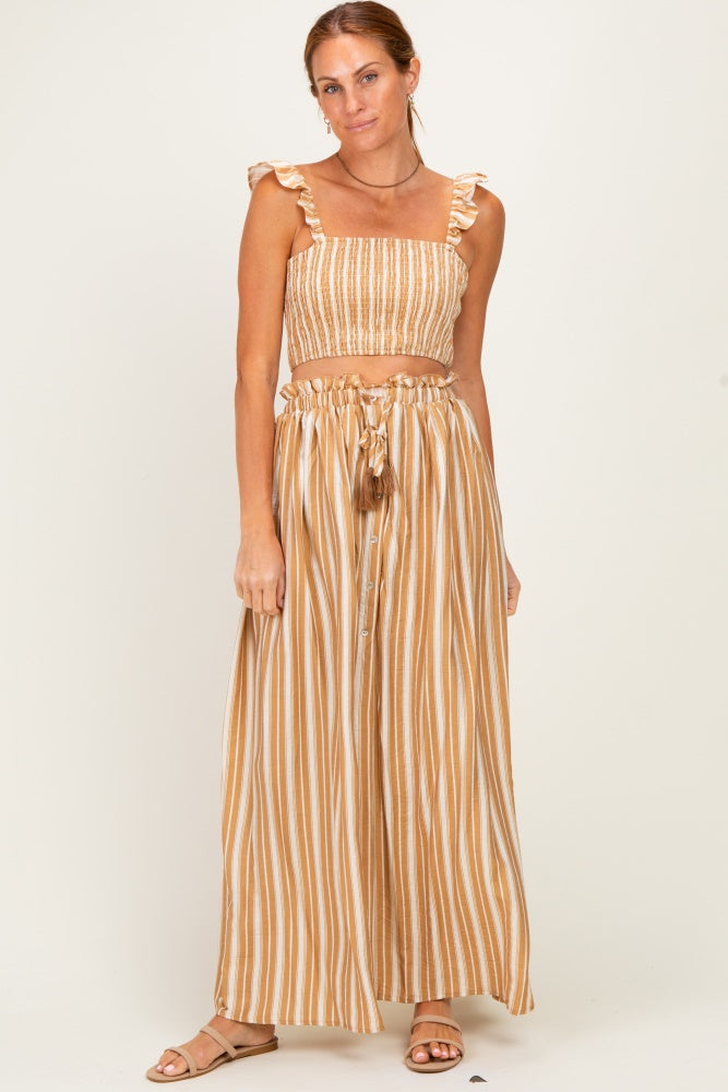 woman wearing a brown and cream striped two-piece set with a smocked crop top and wide-leg pants