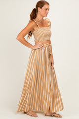 woman wearing a brown and white striped two-piece set with a crop top and maxi skirt, standing profile view