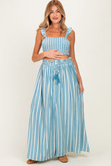 woman wearing a blue and white striped maternity two-piece set with a ruffled crop top and a maxi skirt, holding her baby bump