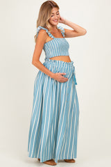 woman wearing a blue and white striped maternity two-piece set with a crop top and a maxi skirt, showing her baby bump
