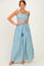 woman wearing a blue and white striped two-piece outfit with a crop top and maxi skirt, featuring ruffled straps and a tied waist