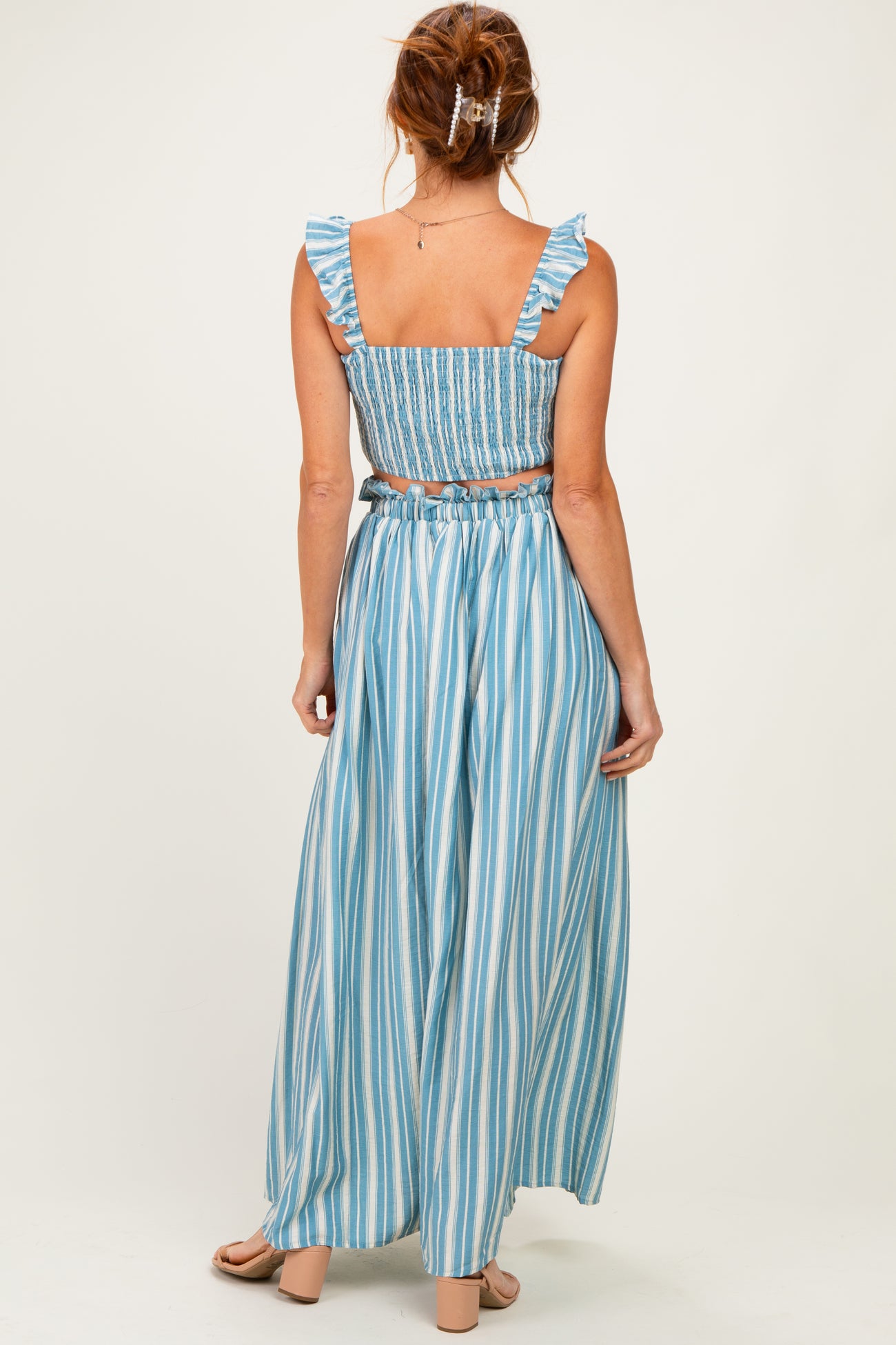 woman wearing a blue and white striped two-piece set with ruffled straps and a flowy maxi skirt