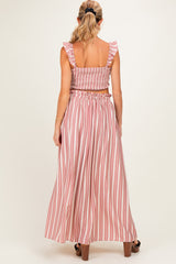 woman wearing a back view of a pink and white striped maternity two-piece set with ruffled sleeves and a flowy skirt