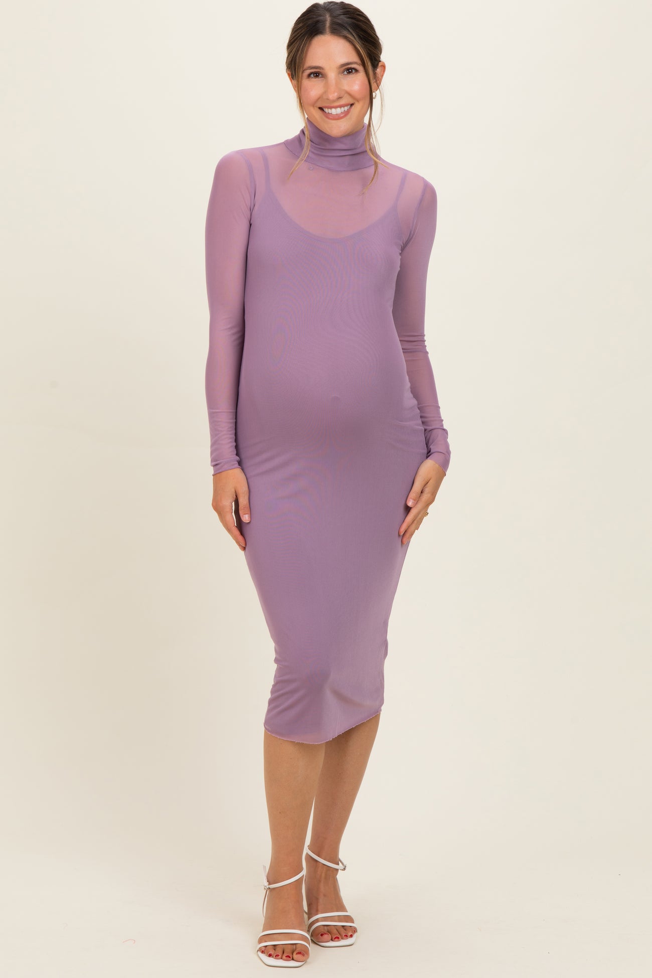 woman wearing a lavender maternity dress with a high neck and long sleeves, showing her baby bump