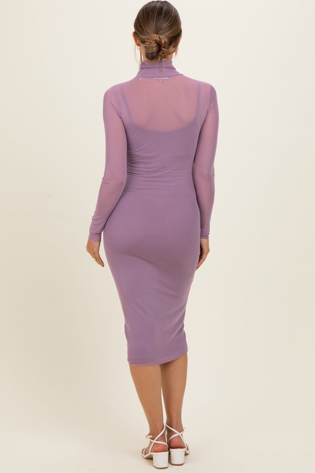 woman wearing a light purple long sleeve maternity dress with a fitted silhouette and sheer back details