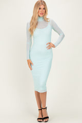 woman wearing a fitted mint green midi dress with a sheer long sleeve overlay and strappy black heels