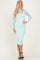 woman wearing a fitted mint green midi dress with a sheer long sleeve overlay and strappy black heels