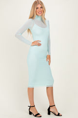 woman wearing a mint green long sleeve bodycon dress with sheer details and black high-heeled sandals