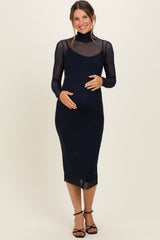 woman wearing a navy blue maternity dress with long sheer sleeves and a fitted silhouette, holding her baby bump