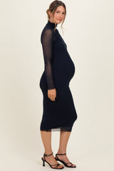 woman wearing a navy long sleeve maternity dress showing her baby bump and paired with black strappy heels