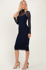 woman wearing a black long sleeve midi dress with a sheer top and a fitted silhouette, paired with strappy nude heels