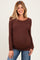 woman wearing a brown long sleeve maternity top that highlights her baby bump and paired with blue jeans
