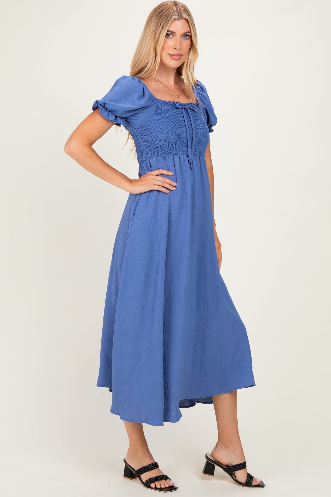 woman wearing a blue smocked maxi dress with puff sleeves and a tie at the neckline