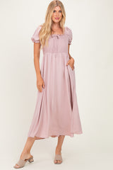 woman wearing a pink puff sleeve maxi dress with a smocked bodice and side pockets