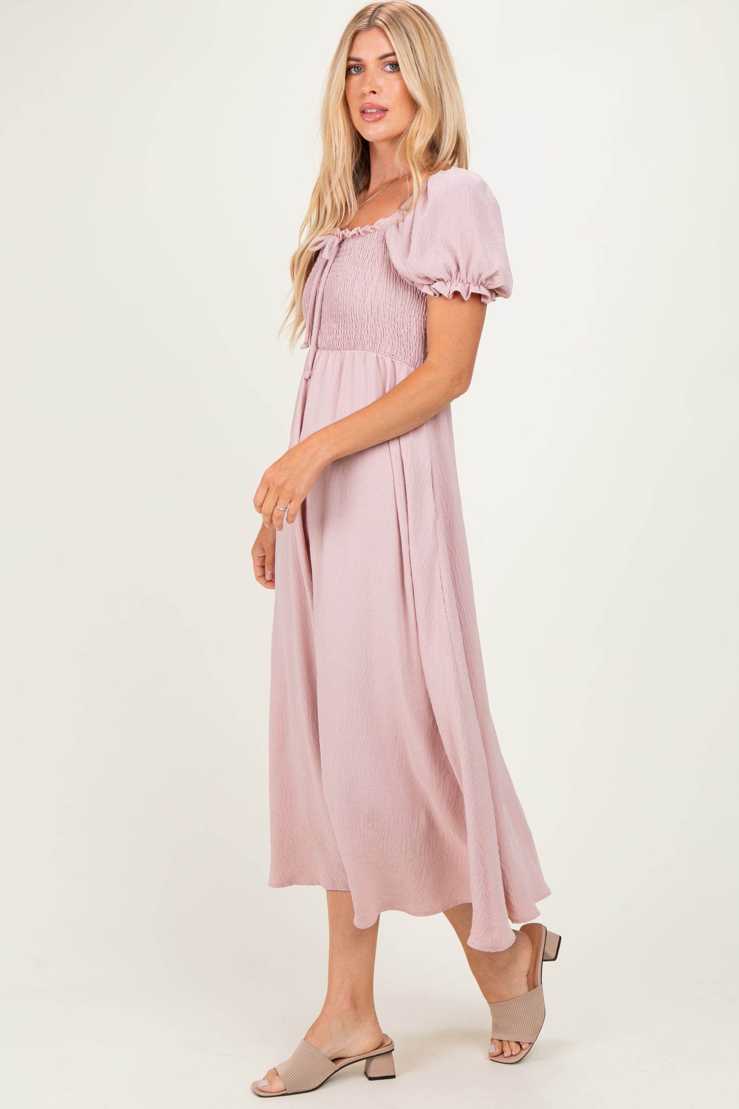 woman wearing a mauve puff sleeve midi dress with a smocked bodice and flowing skirt